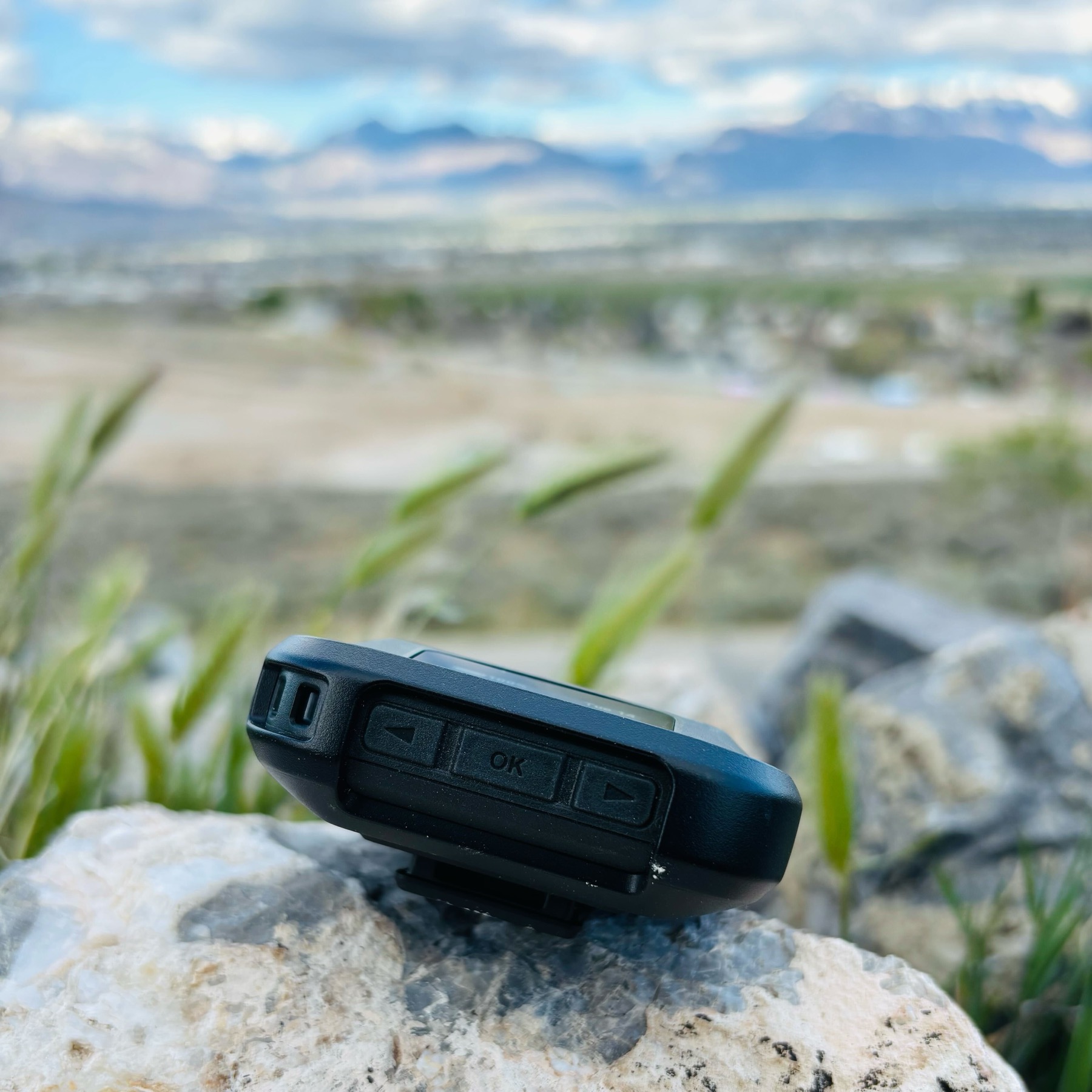 Garmin inReach Messenger side profile showing navigation buttons resting on a rock
