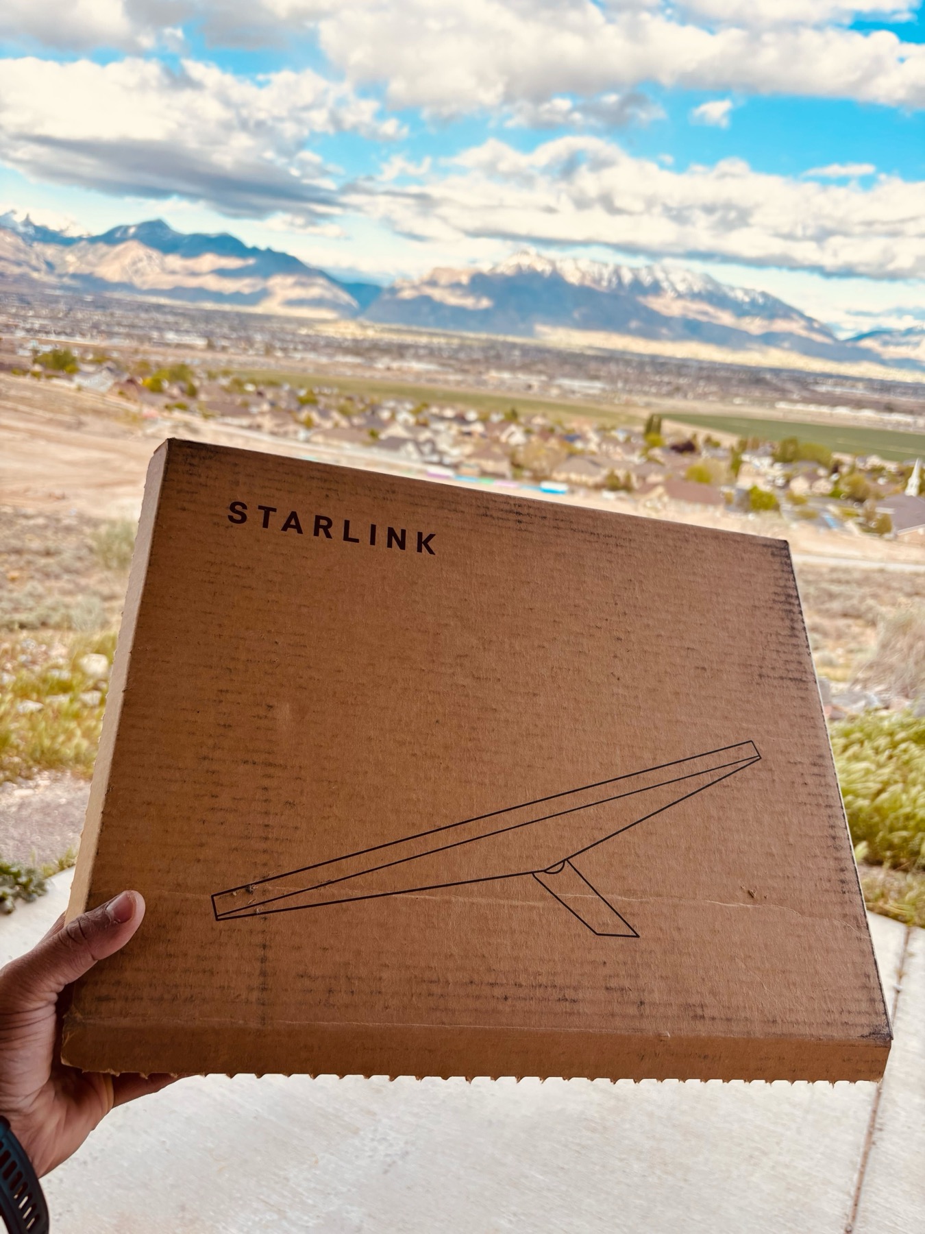 Starlink Mini box being held up against mountain backdrop in Utah