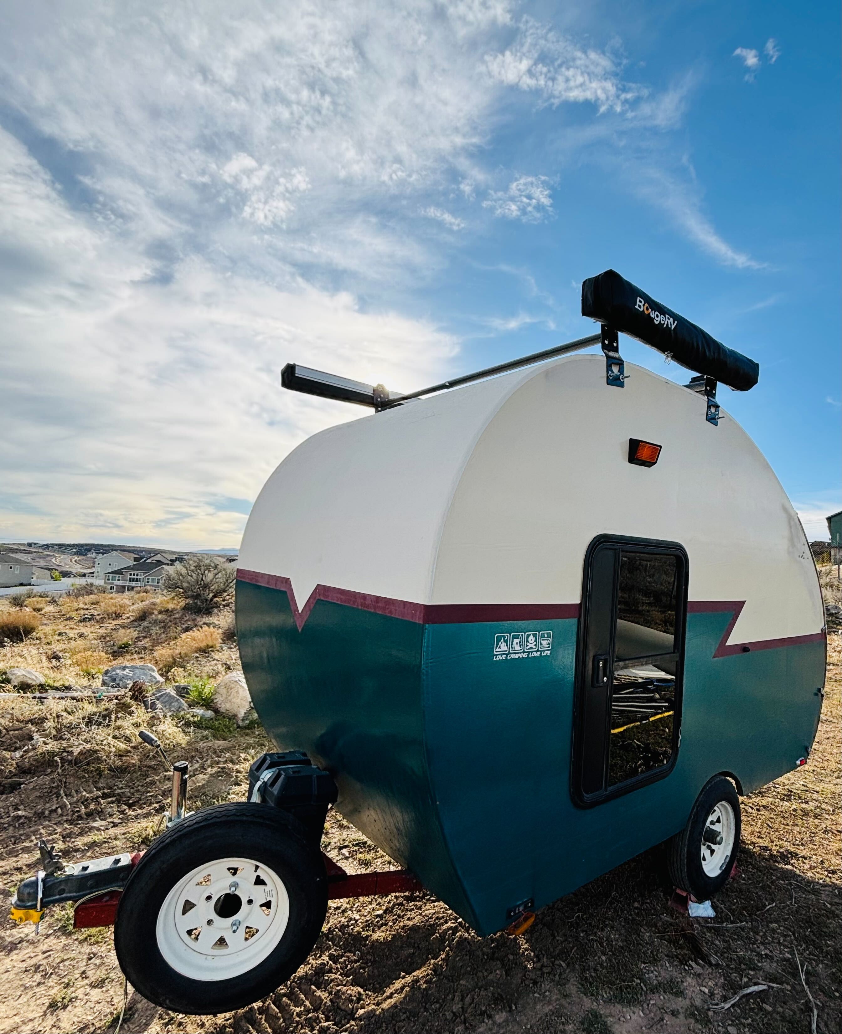 Pearl the teardrop camper on a hillside at golden hour