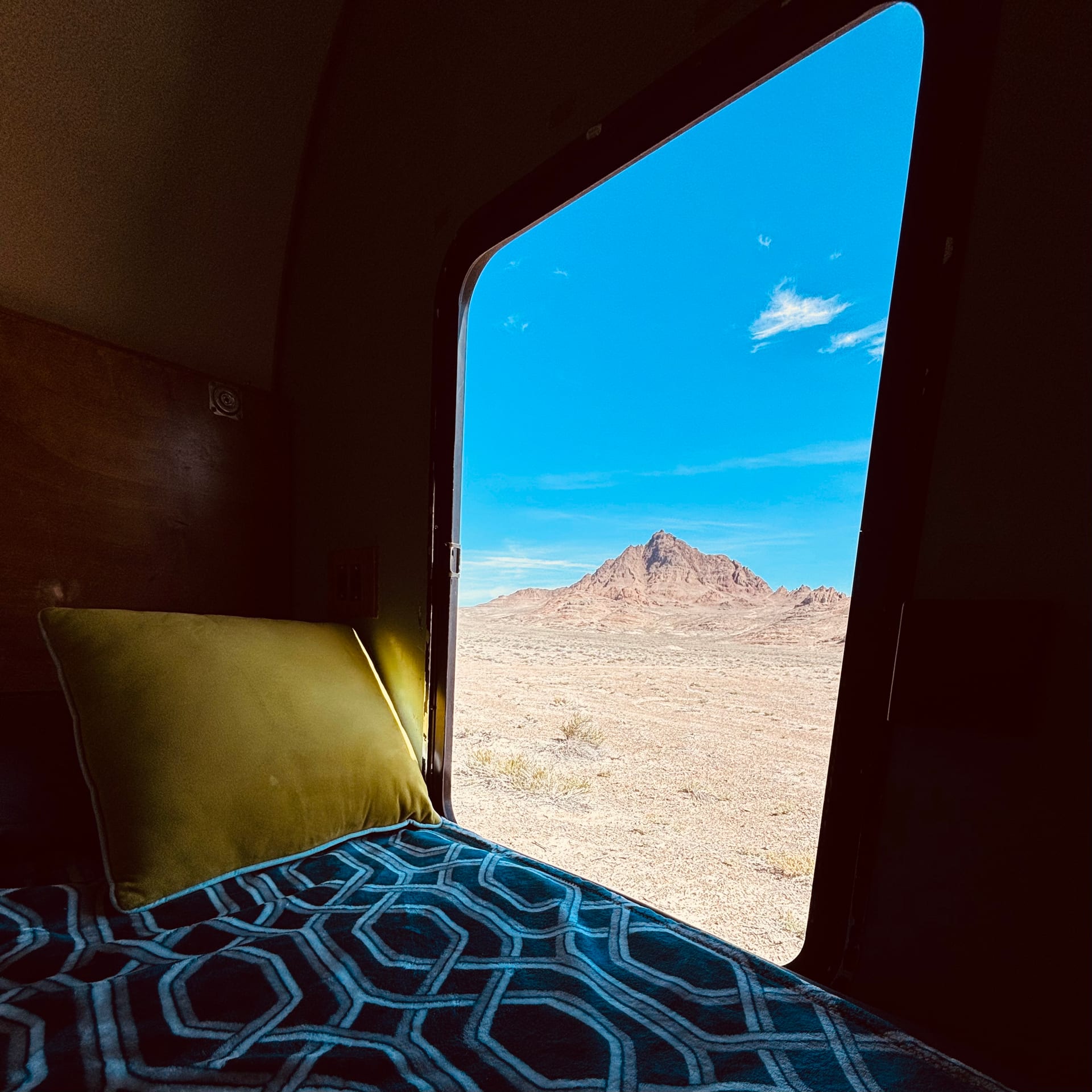 View from inside Pearl camper through the window, looking out at Volcano Peak in the desert