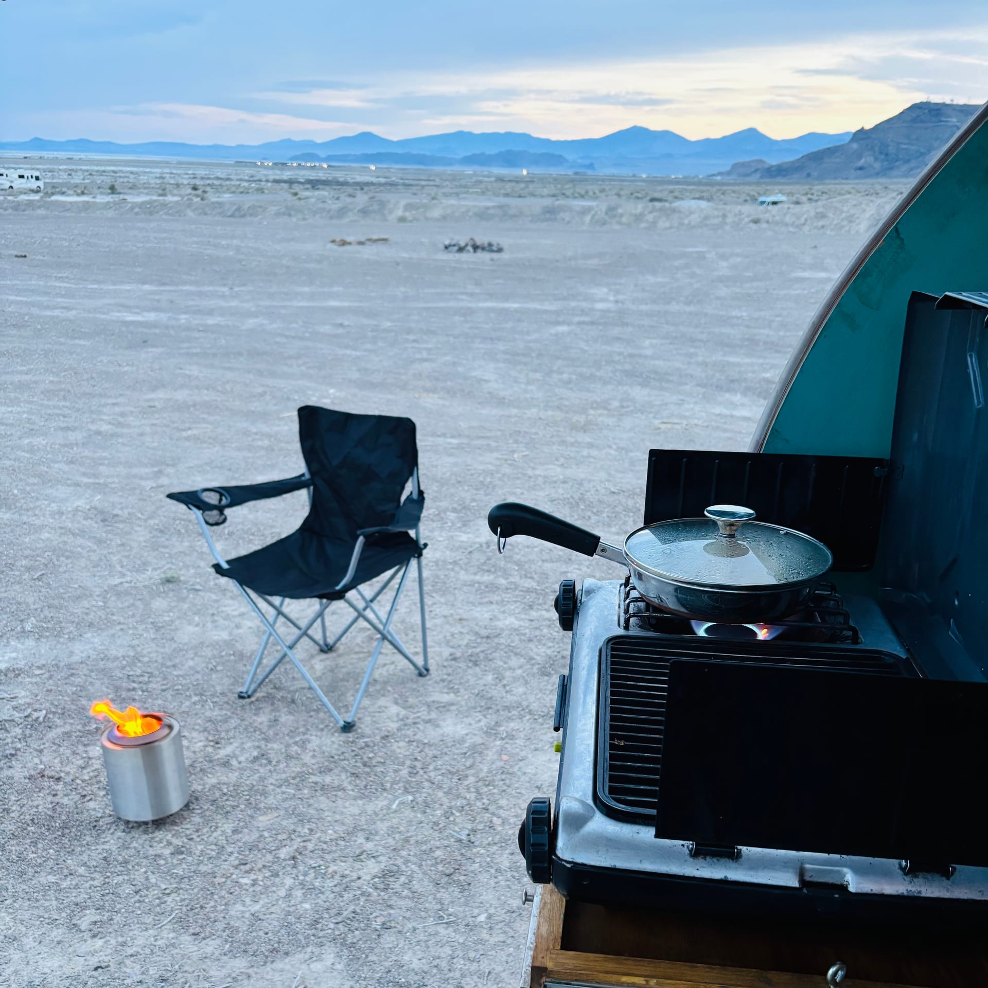 Fire pit glowing at dusk next to Pearl camper
