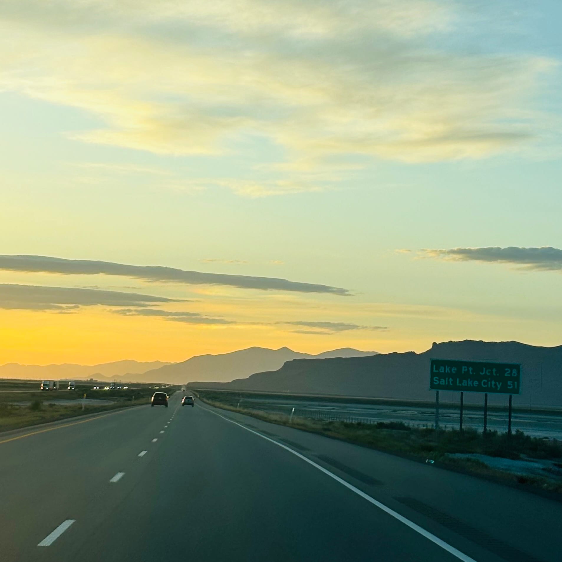 Driving on I-80 heading east toward Salt Lake City at sunset, highway sign showing Salt Lake City 51 miles