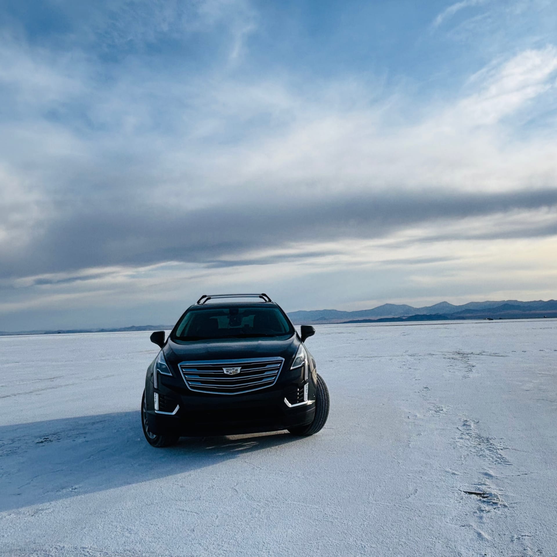Car parked on the white Bonneville Salt Flats under dramatic clouds