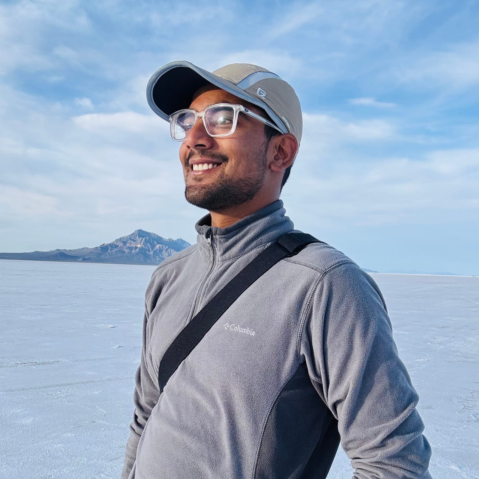 Portrait smiling on Bonneville Salt Flats with mountains and blue sky behind