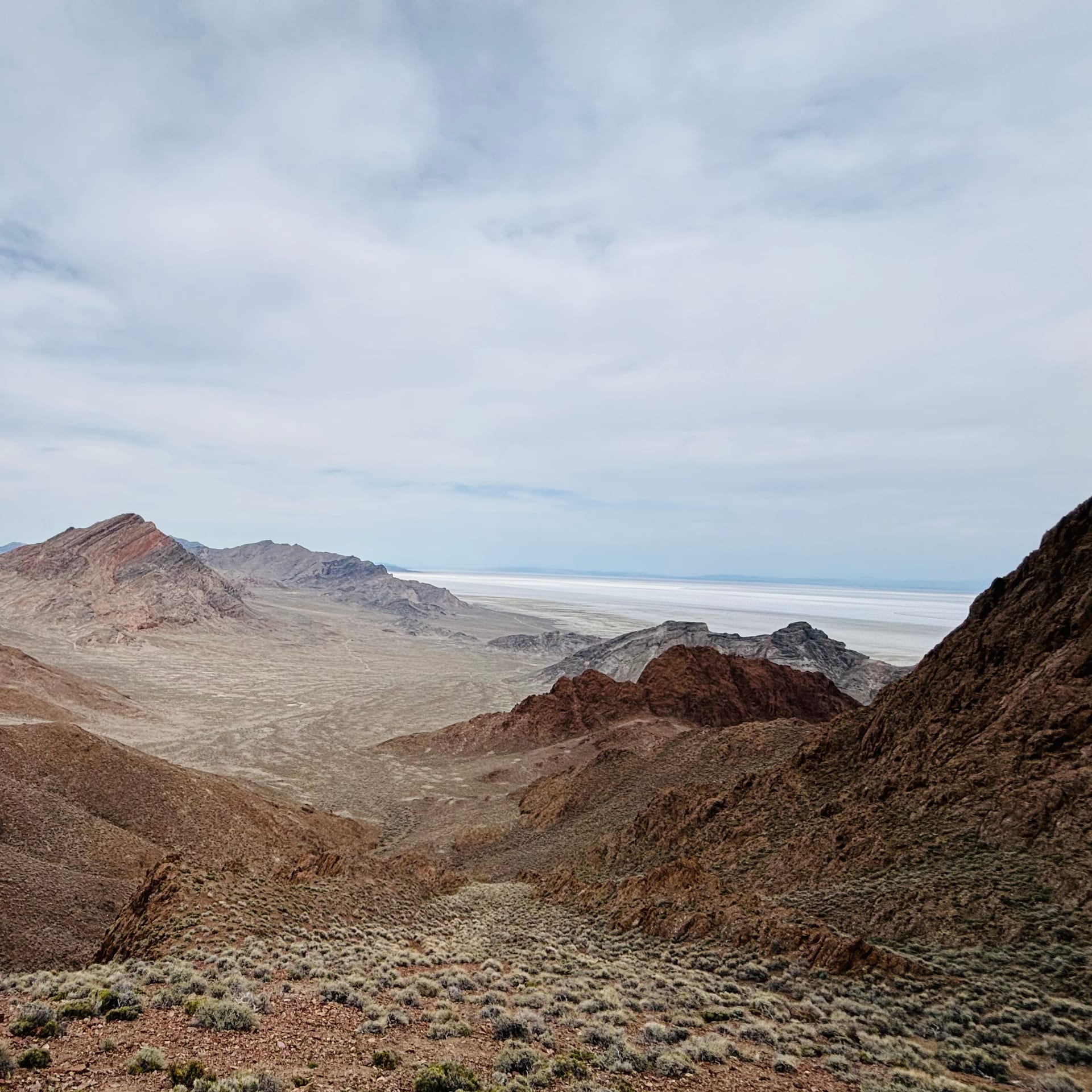 Selfie while hiking Volcano Peak, holding a trekking pole, desert mountains stretching behind